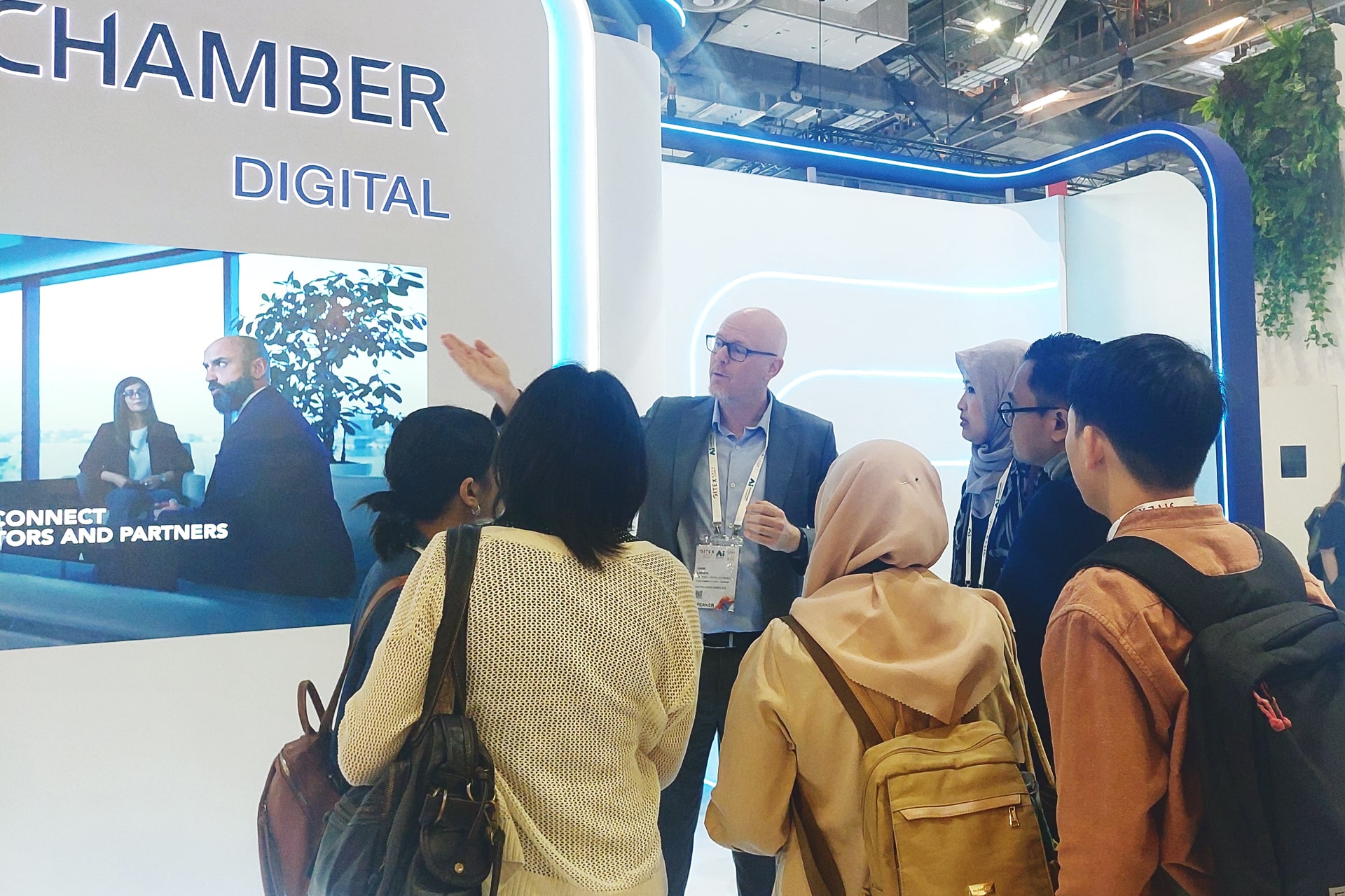 Photo shows Hans Larsen, manager of digital economy acceleration at Dubai Chambers, speaking with journalists from the international media delegation during a booth tour co-led by KrASIA and GITEX Asia organizers.
